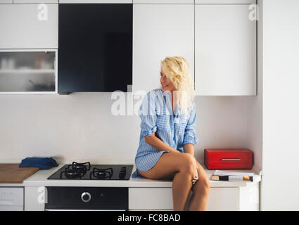 Donna seduta sul banco di cucina Foto Stock
