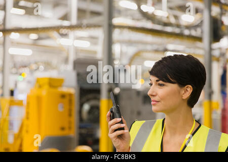 Lavoratore utilizzando un walkie-talkie in fabbrica Foto Stock