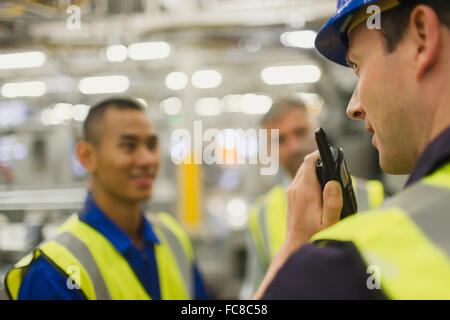 Lavoratore utilizzando un walkie-talkie in fabbrica Foto Stock