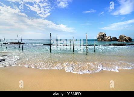 Pali in legno per la pesca su una spiaggia dell'oceano indiano in Sri Lanka Foto Stock