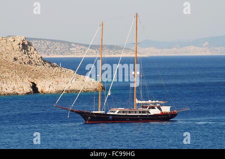 Una twin masted yacht entrando in porto Emborio sull'isola greca di Halki. Foto Stock