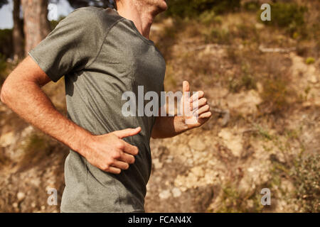 Ritagliato shot del giovane uomo che corre all'esterno. Trail Running allenamento. Foto Stock