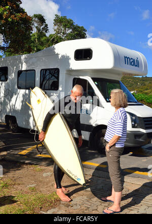 Surfer (maschio) parlando con motoromer (donna) su Hot Water Beach con la Maui Platinum Beach motorhome dietro, Coromandel Peninsula, North Island, NZ Foto Stock