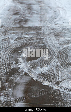 Snowy tracce di pneumatici su cemento. Foto Stock