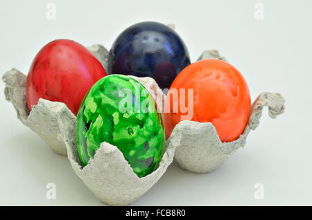 Quattro colorati di uova di pasqua in una scatola di cartone, vicino, isolati su sfondo bianco, orizzontale Foto Stock
