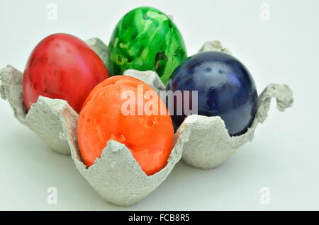 Quattro colorati di uova di pasqua in una scatola di cartone, vicino, isolati su sfondo bianco, orizzontale Foto Stock