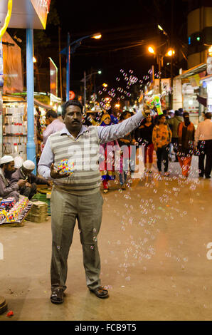 Il gorgogliamento della pistola di soffiaggio del fornitore bolle di sapone in aria sulla strada principale, città bazaar, mahabaleshwar Foto Stock