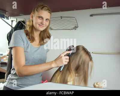 6 anno vecchia ragazza giocando nella bambola mentre mamma pigtail trecce di capelli, in seconda classe, trasporto in treno Foto Stock