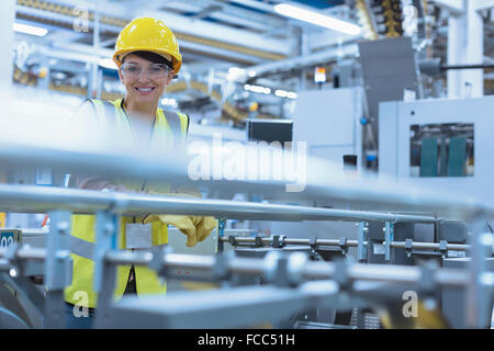 Ritratto sorridente lavoratrice a macchinari in fabbrica Foto Stock