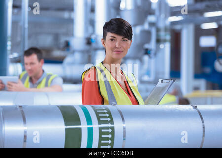 Ritratto fiducioso lavoratore femmina con blocco per appunti in fabbrica Foto Stock