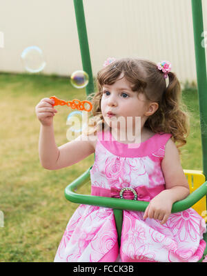 Carino bambina basculante in altalena e giocare con le bolle di sapone Foto Stock