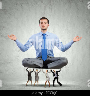 Giovane imprenditore meditando supportati da colleghi di lavoro Foto Stock