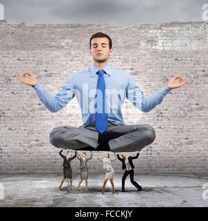 Giovane imprenditore meditando supportati da colleghi di lavoro Foto Stock