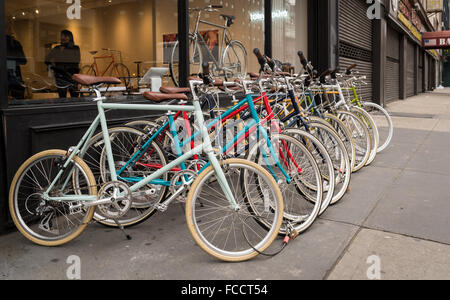 Biciclette colorati disposti in una linea sul marciapiede fuori da un negozio di biciclette (Tokyobike) in NYC. Foto Stock