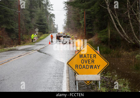 Lavoratori di emergenza posizionando cartelli di avvertimento sulla sede stradale allagato nello Stato di Washington, USA. Acque piovane copre la strada. Foto Stock