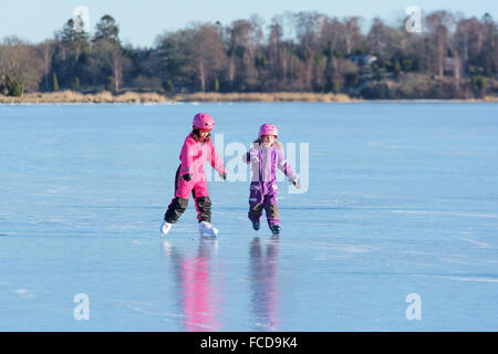 Listerby, Svezia - 17 Gennaio 2016: Due ragazze sono avente un certo divertimento sul mare ghiacciato ghiaccio. Il ghiaccio è liscio e il paesaggio Foto Stock