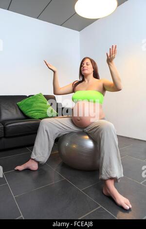 Francia, incinta giovane donna facendo esercizi yoga sul palloncino gonfiabile Foto Stock