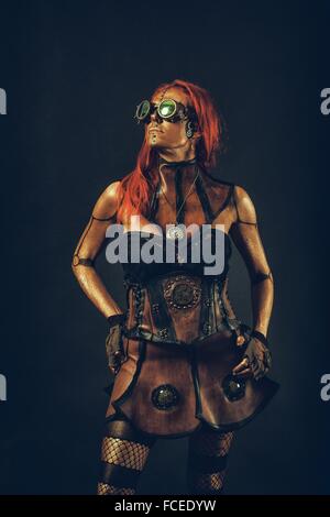 Robot steampunk donna con i capelli rossi in piedi con le mani sui fianchi Foto Stock