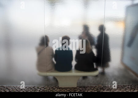 Persone in attesa ad una fermata di un autobus shelter. Foto Stock