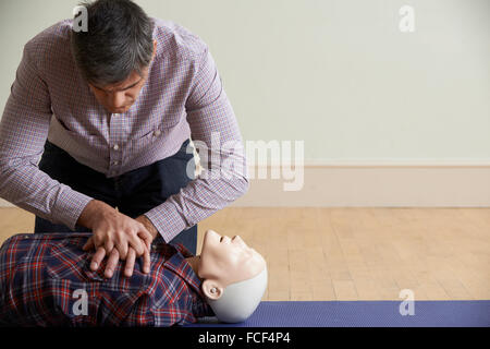Uomo con tecnica di esecuzione della rianimazione cardiopolmonare su manichino nella prima classe di aiuto Foto Stock