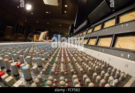 Vista laterale di qualcuno che lavora su un ssl e serie di missaggio del suono di scrivania e Apple Mac con studio di altoparlanti in uno studio di registrazione Foto Stock