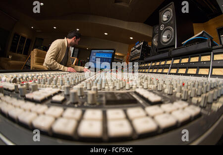 Vista laterale di qualcuno che lavora su un ssl e serie di missaggio del suono di scrivania e Apple Mac con studio di altoparlanti in uno studio di registrazione Foto Stock