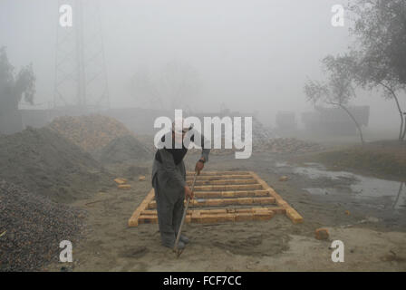 Peshawar. Il 22 gennaio, 2016. Un operaio lavora durante la fitta nebbia nel nord-ovest del Pakistan a Peshawar, a gennaio 22, 2016. Nebbia fitta inghiottito diverse parti del Punjab e a Peshawar, causando il traffico stradale e i voli delle interruzioni. Credito: Umar Qayyum/Xinhua/Alamy Live News Foto Stock