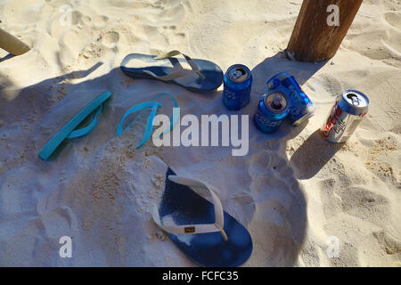 Il flip flop e lattine di birra sotto un ombrellone sulla spiaggia di Cancun, Messico Foto Stock