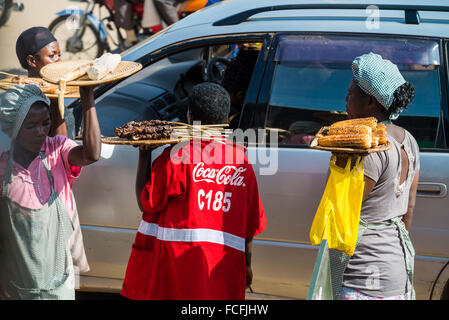 Venditori ambulanti vendono beni alle persone su bus locali passando attraverso i villaggi sulla strada fuori da Kampala, Uganda, Africa Foto Stock