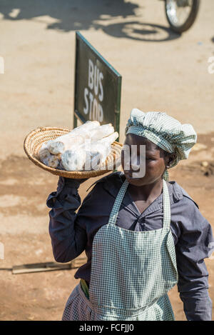 Venditori ambulanti vendono beni alle persone su bus locali passando attraverso i villaggi sulla strada fuori da Kampala, Uganda, Africa Foto Stock