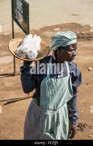 Venditori ambulanti vendono beni alle persone su bus locali passando attraverso i villaggi sulla strada fuori da Kampala, Uganda, Africa Foto Stock