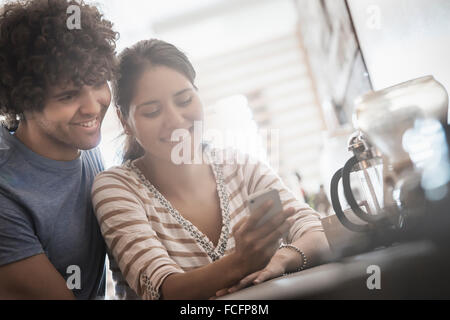 Loft living. Un giovane, giovane uomo e donna guardando un telefono intelligente Schermo. Foto Stock