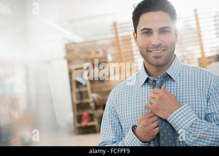 Un uomo regolando la cravatta guardando la telecamera. Foto Stock