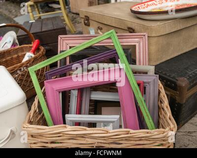 Diversi dipinti colorati delle cornici in legno in un cestello per la vendita presso un fornitore in Hay-on-Wye, Wales, Regno Unito, Europa. Foto Stock