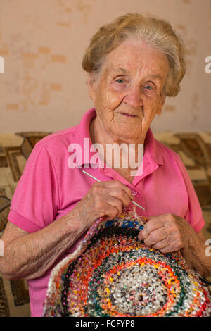 Una donna anziana maglieria a crochet. Foto Stock