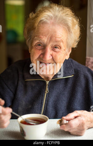 Donna anziana bere il tè in cucina. Foto Stock