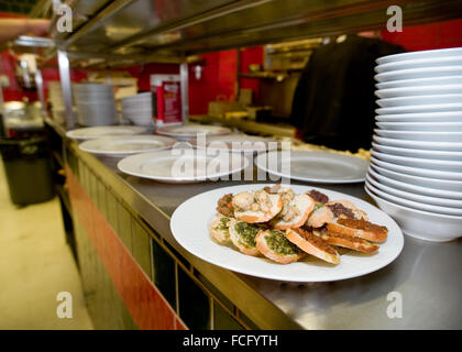 Varietà di bruschette pronto per il ritiro su un piatto di portata in ceramica bianca in un ristorante italiano. Foto Stock