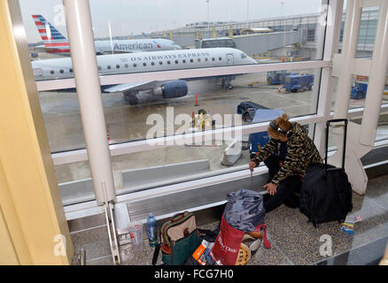 (160122) -- WASHINGTON D.C., il 22 gennaio 2016 (Xinhua) -- un passeggero si appoggia sul pavimento in attesa per il suo volo presso l'Aeroporto Nazionale Ronald Reagan di Washington, 22 gennaio 2016. Washington, DC e altri cinque Stati degli Stati Uniti lungo gli Stati Uniti Costa est di giovedì ha dichiarato lo stato di emergenza come era la regione stessa di controventamento in una storica tempesta di neve durante il fine settimana che è stato previsto per eseguire il dump di fino a 2 metri di neve. Le principali compagnie aeree hanno cominciato a cancellare voli per venerdì e sabato. Secondo FlightAware, un tracking voli site, almeno 2.000 voli il venerdì e un altro 3.000 sabato w Foto Stock