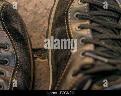 Tagliata di close-up di pelle nera e scarpe in pelle scamosciata con lacci sulla passerella di pietra. Foto Stock