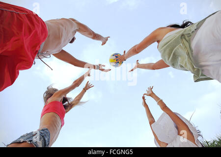 Un gruppo di giovani giocando a pallavolo in esterno Foto Stock