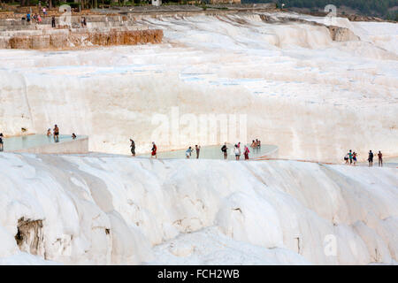 I turisti a piedi lungo le piscine artificiali di Pamukkale con persone intorno al crepuscolo Foto Stock