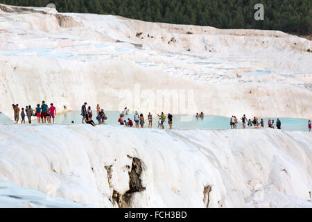 I turisti a piedi lungo le piscine artificiali di Pamukkale con persone intorno al crepuscolo Foto Stock