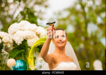 La sposa è in possesso di farfalla sul suo dito. Foto Stock