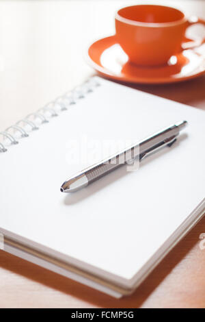 Penna sul fustellato aperto bianco per notebook con tazza di caffè sulla scrivania, stock photo Foto Stock