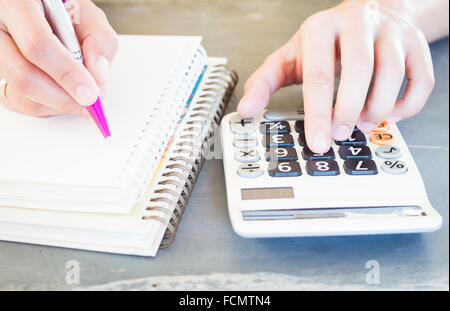 Mano che tiene la penna e premendo i pulsanti di calcolatrice, stock photo Foto Stock