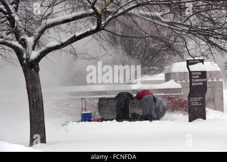 Washington, DC, Stati Uniti d'America. 23 gen 2016. Due uomini senza tetto caldo se stessi in corrispondenza di una uscita di vapore su Constitution Avenue a Washington, DC, Stati Uniti, 23 gennaio, 2016. Oltre 43cm di neve sono stati riportati in Washington, DC il sabato mattina, come la tempesta di neve mantiene fino a mezzanotte. Credito: Yin Bogu/Xinhua/Alamy Live News Foto Stock