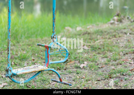 Colorate e rusty horse swing su un parco giochi per bambini Foto Stock