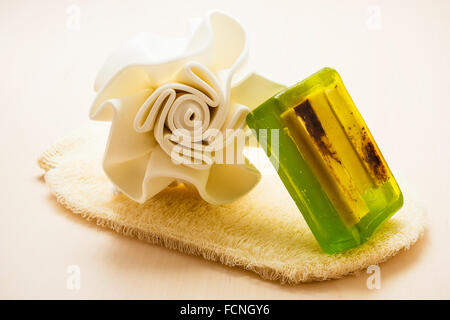 La bellezza e la cura della pelle. Closeup spa prodotti accessori da bagno in spugna sapone verde e massaggio scrub guanto sulla tavola di legno. Foto Stock