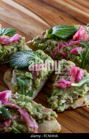 In prossimità di una fetta biscottata di pane piatto condito con una casa fatta diffondere utilizzando avocado e cavolo fermentato e poi rabboccato wit Foto Stock