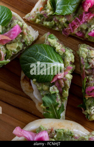 In prossimità di una fetta biscottata di pane piatto condito con una casa fatta diffondere utilizzando avocado e cavolo fermentato e poi rabboccato wit Foto Stock